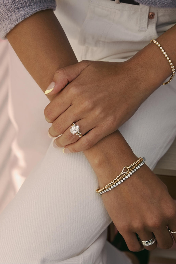 A woman showing off a diamond engagement ring and multiple bracelets from the Ethereal Romance Collection.