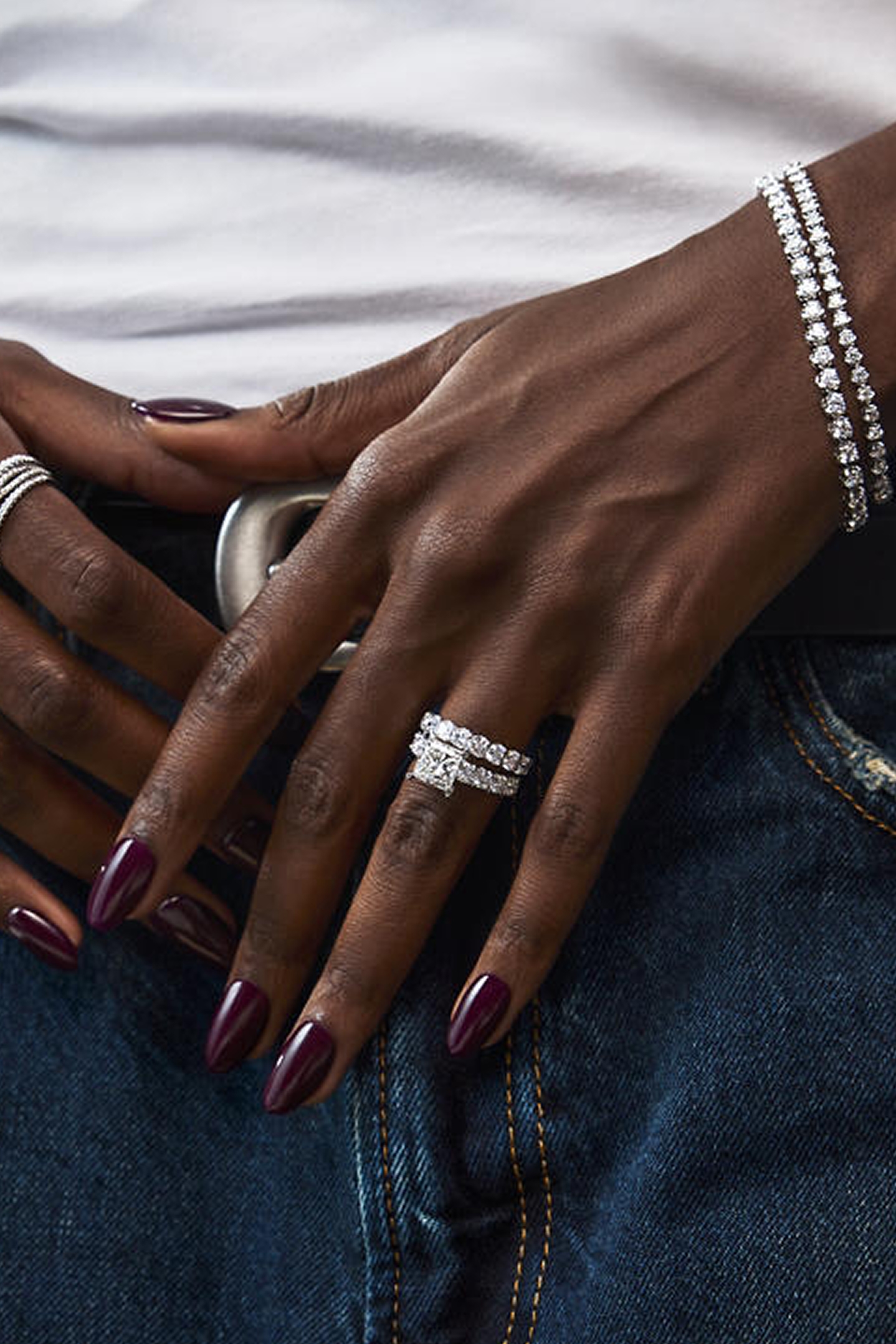A woman showing off a diamond engagement ring and tennis bracelets from the Grand Glamour Collection.