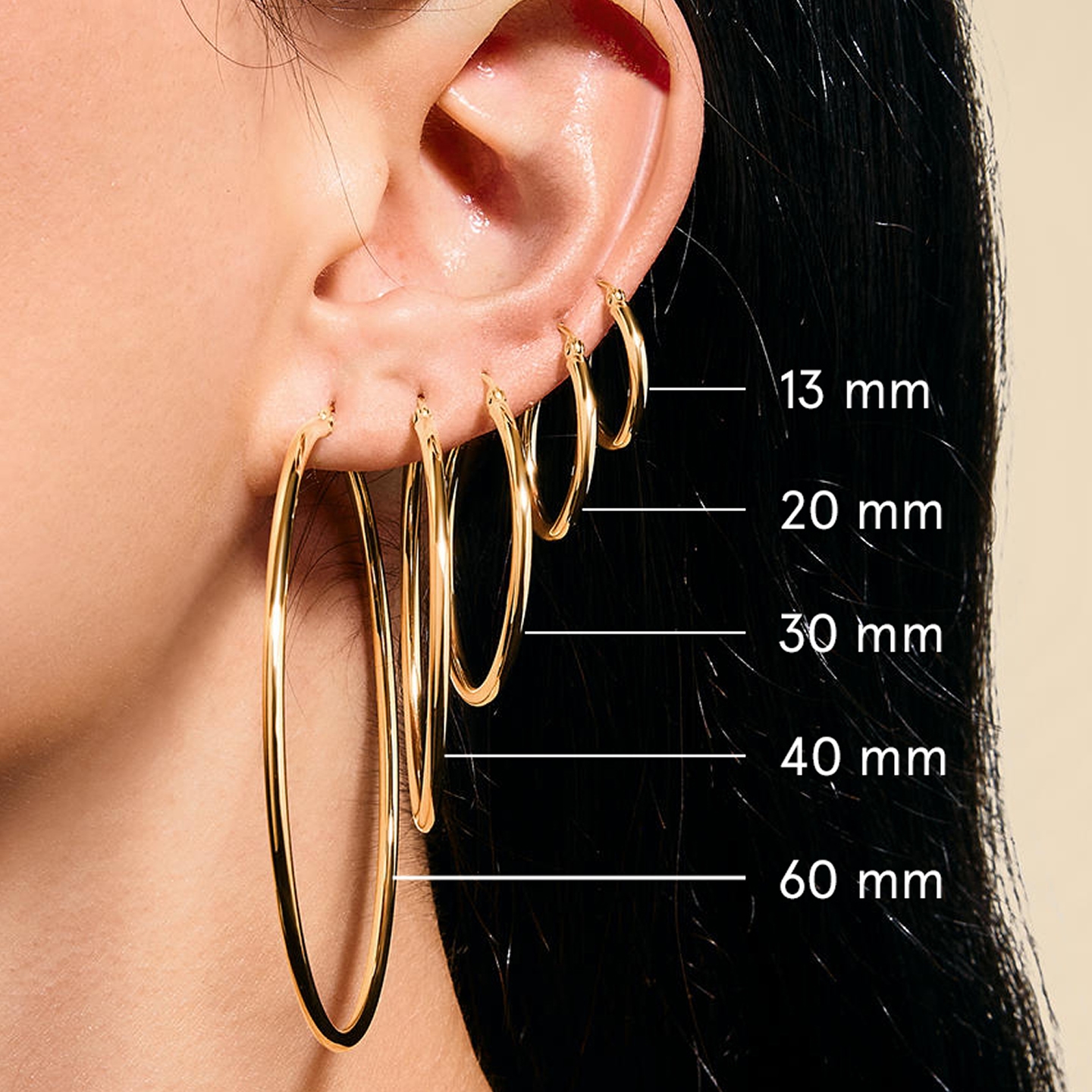 A model wearing five different gold hoop earrings, showing the difference in size.