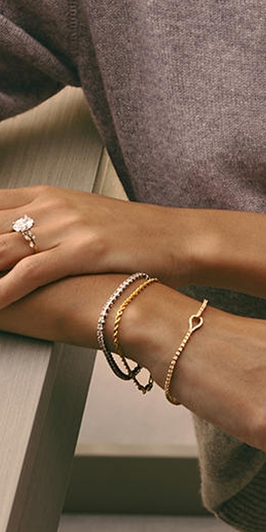 Multiple gold bracelets and rings styled and stacked.
