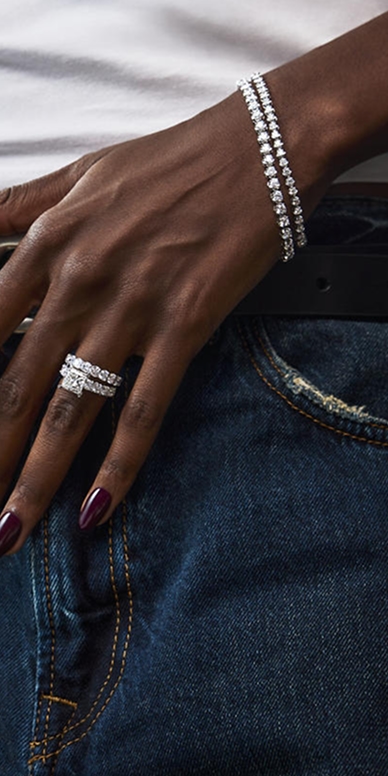 A woman wearing multiple diamond rings and tennis bracelets from the Grand Glamour collection.