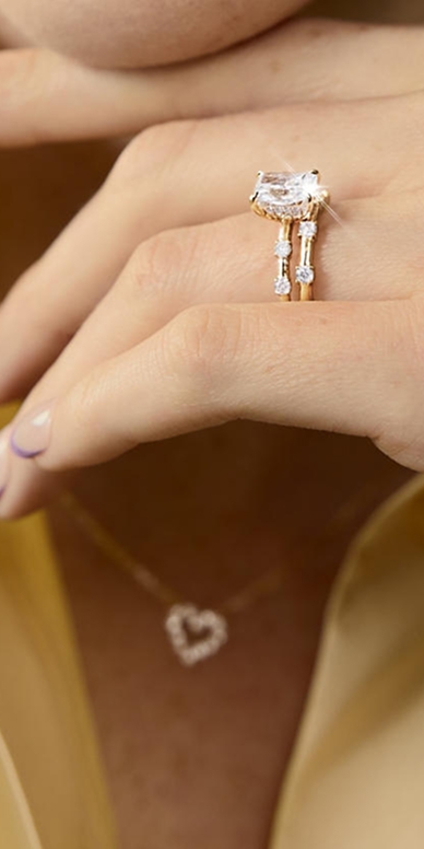 A woman showing off her gold, diamond ring from the Modern Muse Collection.