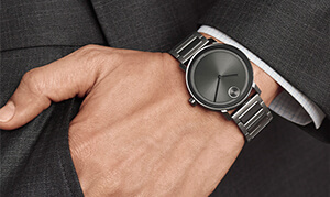 A man's wrist displaying a black on black analog watch