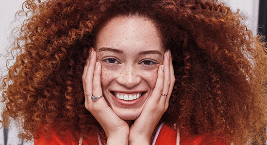 A young, smiling woman with red, frizzy hair