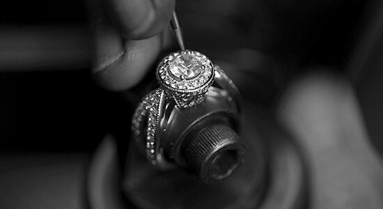 A jeweler working with a fine tool to repair a diamond ring